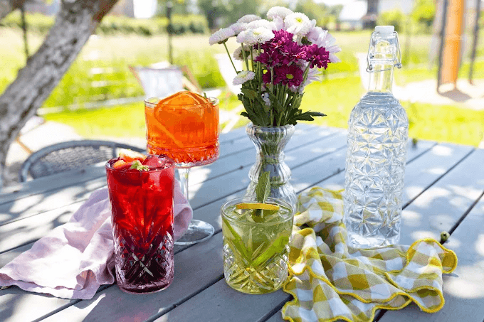 Kolorowe lemoniady i drinki w rzeźbionych szklankach na ogrodowym stole