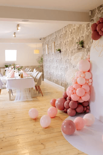 Sala przyjęć udekorowana girlandą różowych balonów