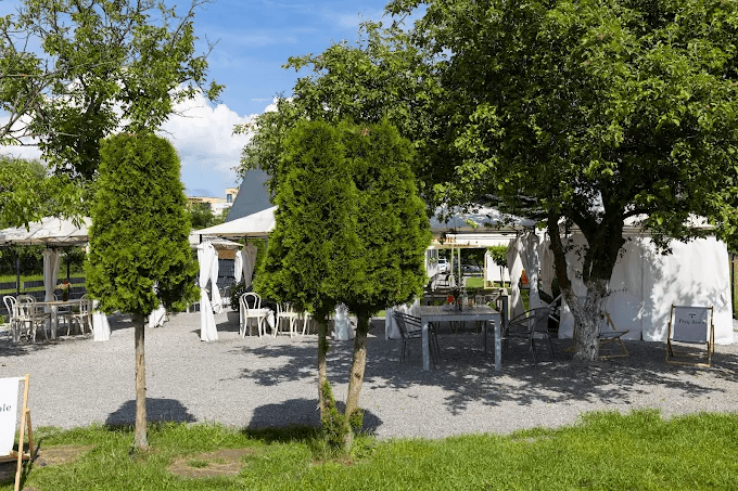 Zadaszone strefy ogrodowe restauracji ze stolikami wśród drzew
